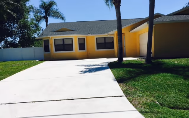 Single-story yellow facility exterior with curved driveway and palm trees.