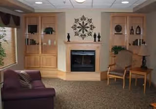Cozy common room with a central fireplace flanked by built-in shelves, chairs and a sofa.