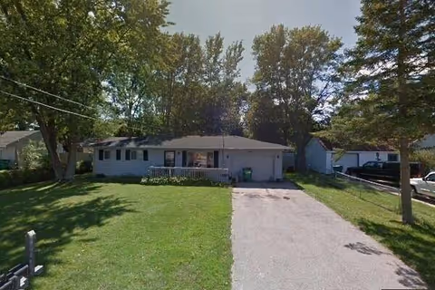 Exterior of Lucia House, a single-story senior facility, with driveway, lawn, and trees.