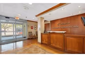 Reception area of Lakeview Nursing and Rehabilitation Center with a wooden front desk, a sign on the wall behind the desk displaying the facility name, a glass entrance door, and chairs along the wall near the entrance.