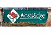 Green WestRidge sign with a red bird logo on a stone base.