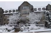 Snowy exterior of Inglis House with bare trees and snow-covered landscaping.