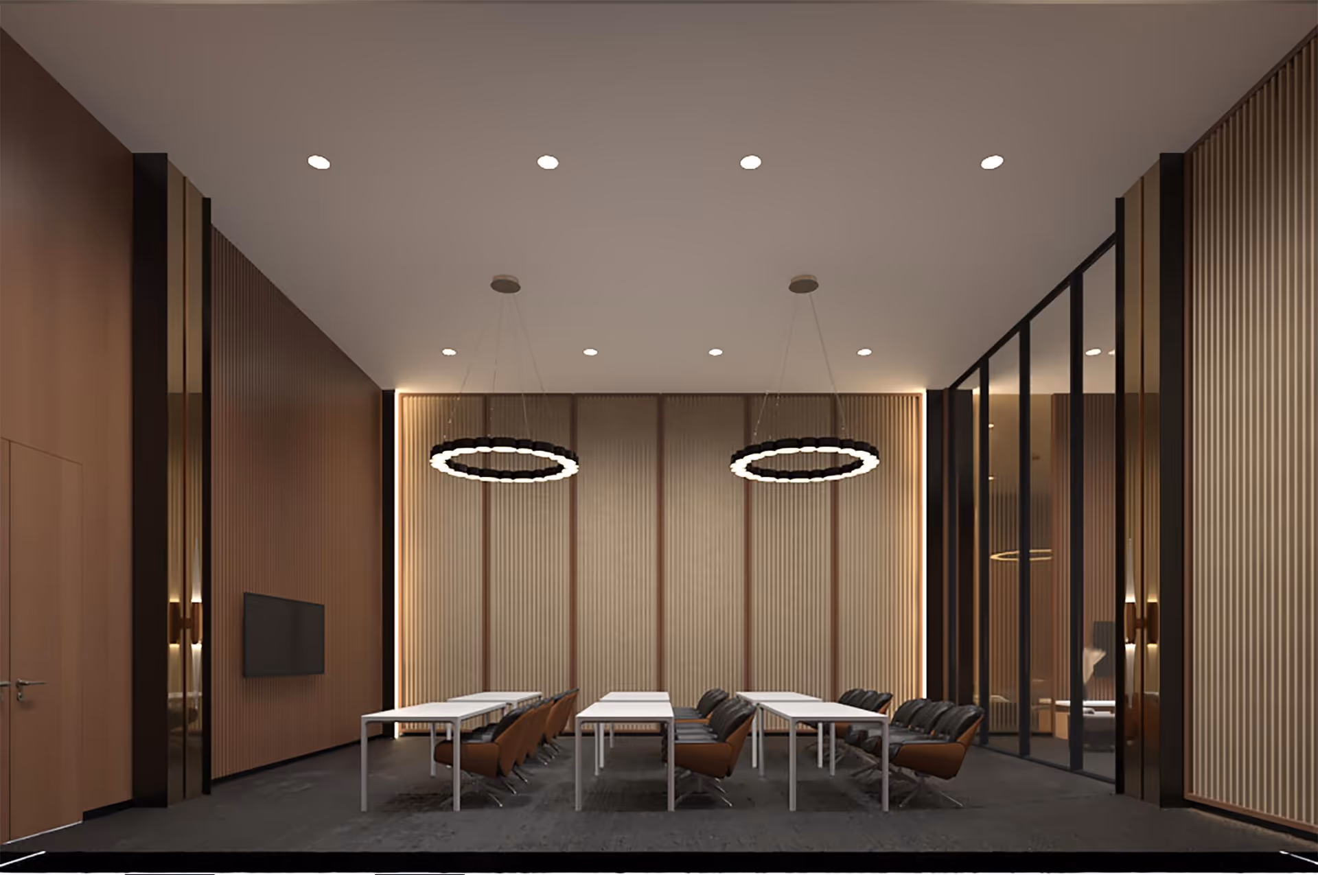 A modern conference or meeting room with three white tables arranged in a row, each accompanied by brown and black chairs. The room features vertical wooden paneling on the walls, two circular pendant lights hanging from the ceiling, and a flat-screen TV mounted on the left wall. The right side has large glass panels with black frames, and the floor is covered with dark carpeting.