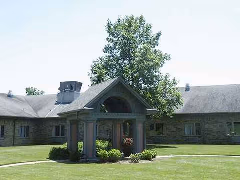 Stone building exterior with a covered entryway and manicured lawn.