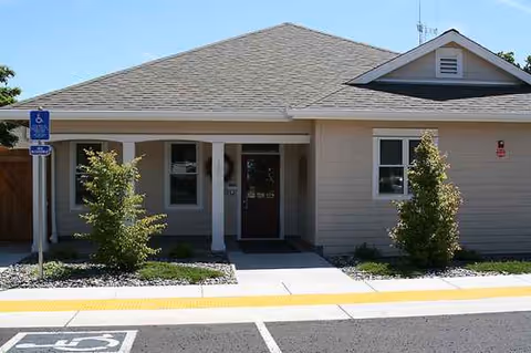 Front view of Summit Springs Village exterior entrance with handicap sign and shrubs.