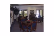 A senior living common area with round tables, chairs, and a plant centerpiece.