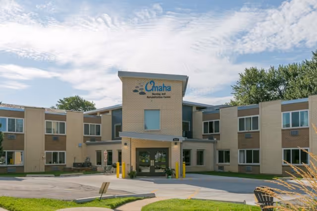 Front view of Omaha Nursing and Rehabilitation Center, a two-story brick building with a covered entrance and surrounding landscaping.