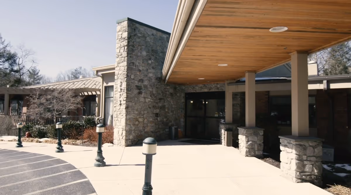 Front entrance of Paramount Senior Living Chambersburg with stone pillars and wooden overhang.
