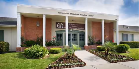 Front view of a brick nursing center entrance with columns and landscaped walkway.