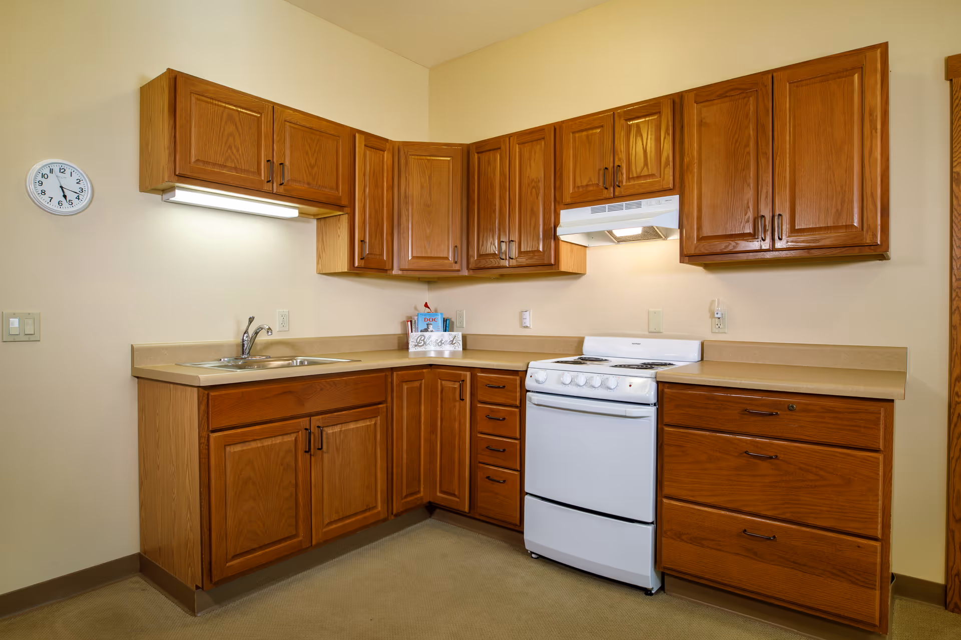 Small kitchen with oak cabinets, laminate countertops, a white stove, and a sink.