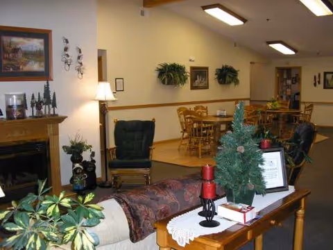 Cozy interior lounge in a senior living facility with fireplace, sofas, and potted plants.