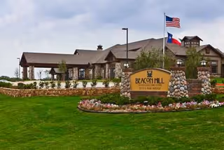 Front exterior of Beacon Hill senior living facility with stone sign and manicured lawn