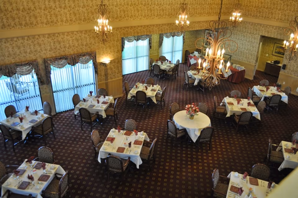 Overhead view of an elegant dining room with multiple set tables, chandeliers, and floral centerpieces.