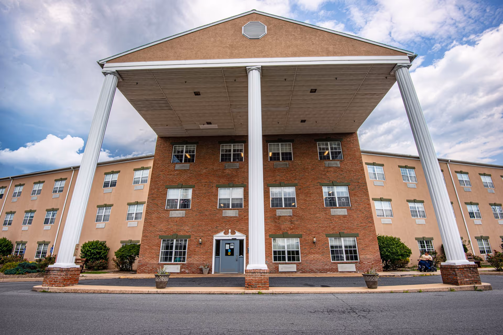Front exterior of a three-story nursing facility with a large covered entrance supported by tall white columns.