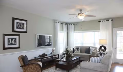 Lakeside Crossing living room with sofa, coffee table, TV, and large windows.