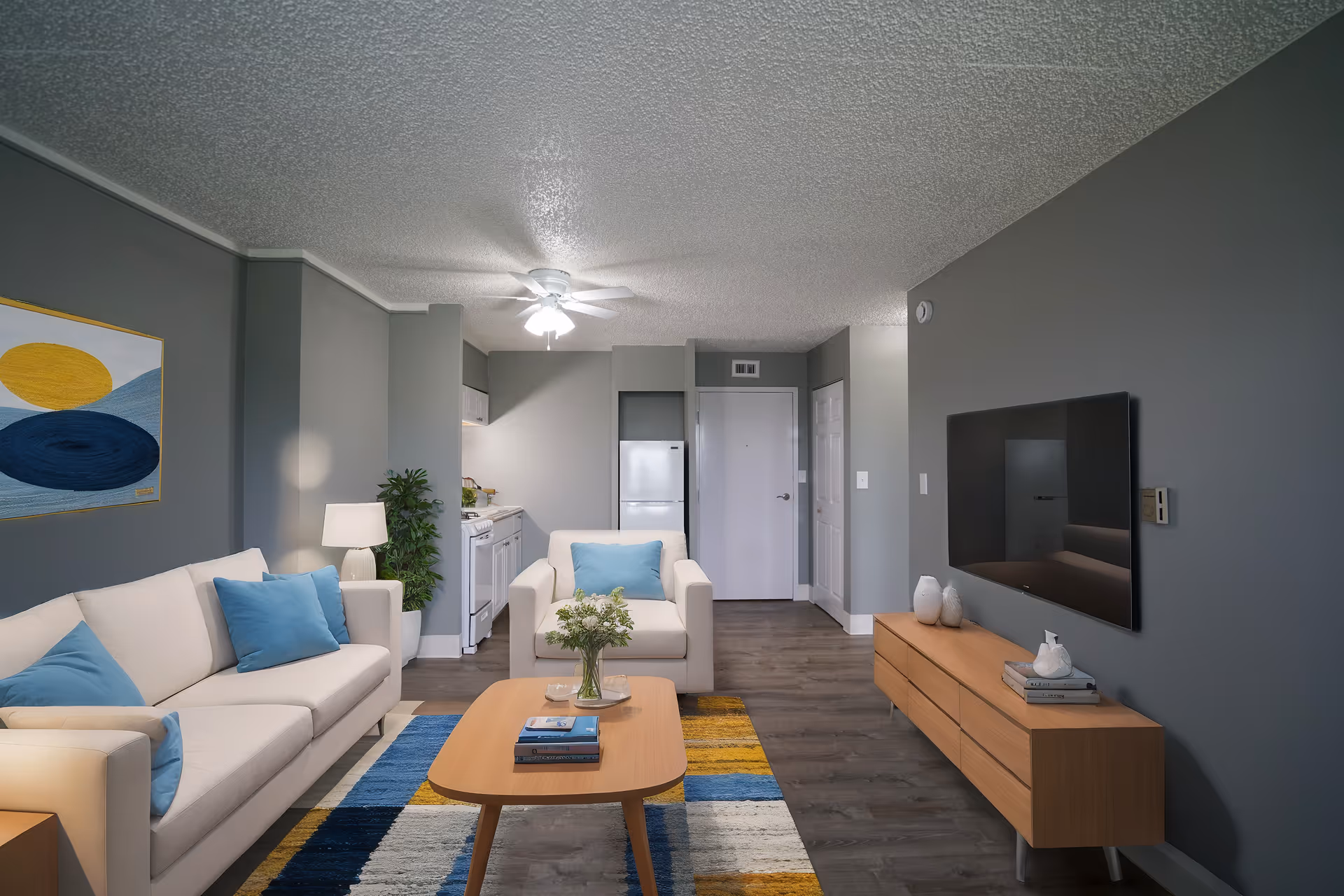 Modern senior living living room with white sofas, blue cushions, a wooden coffee table, and TV.