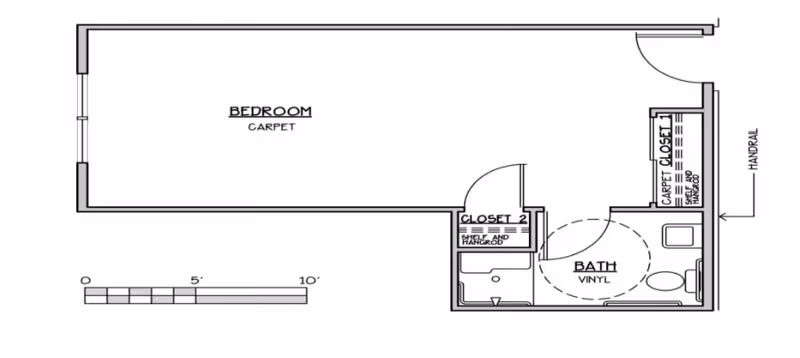 Architectural floor plan showing a bedroom with carpet flooring, two closets with shelves and hangrods, and a bathroom with vinyl flooring including a toilet and a shower area. The plan includes a handrail near the entrance.