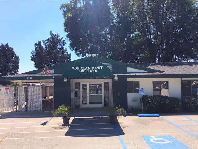 Front entrance of Montclair Manor Care Center with a green awning, potted plants, and marked handicapped parking spaces.