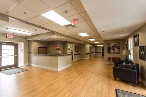Bright lobby area with a reception desk, hallway, and seating in a senior living facility interior.