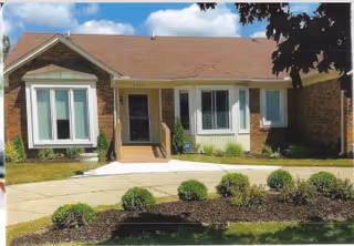 A single-story brick building with a landscaped front yard and a walkway.