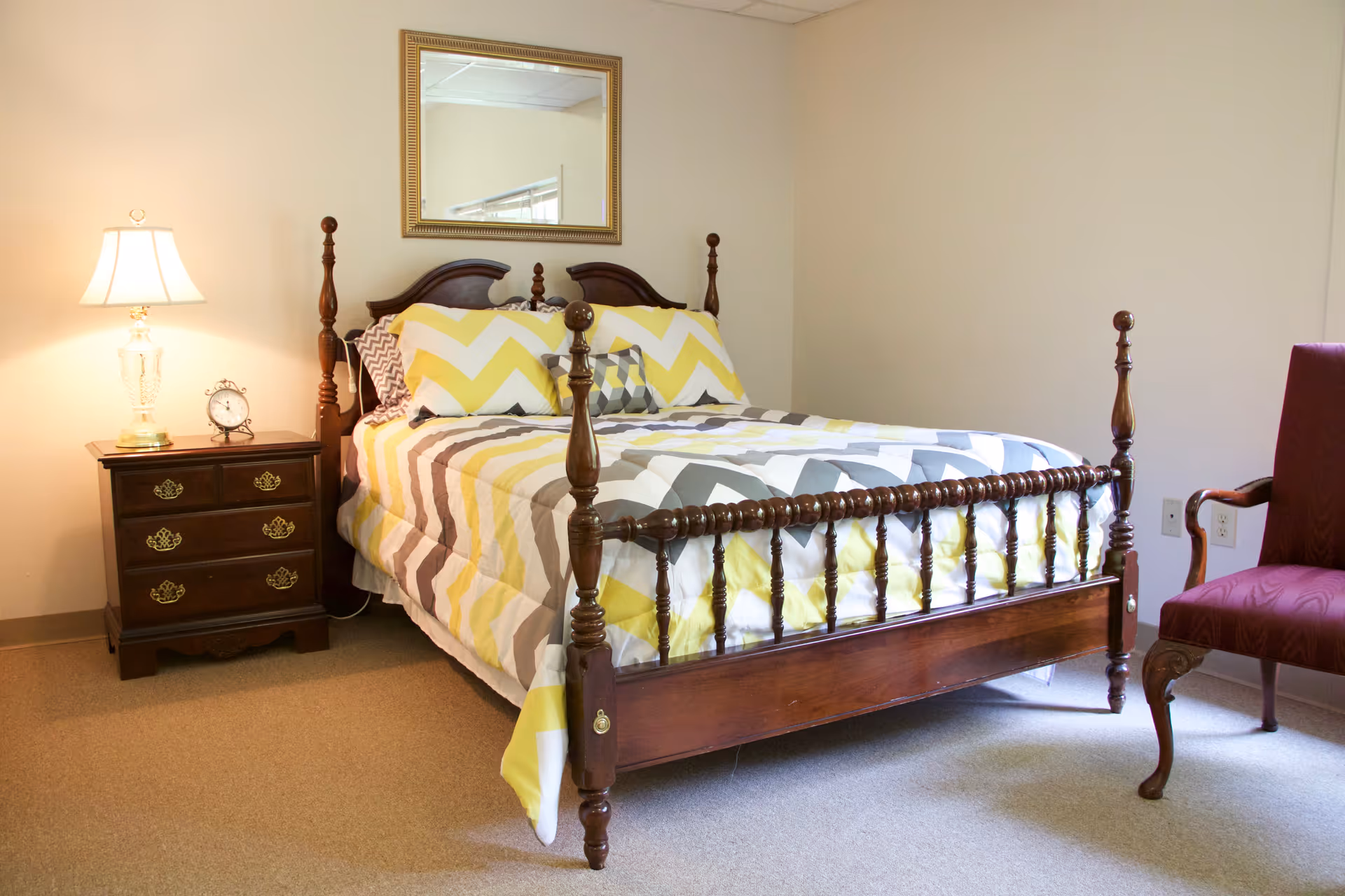 Traditional wooden four-poster bed with chevron quilt in a warmly lit bedroom.