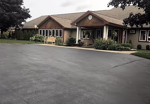 Front exterior of a single-story senior living facility with a covered entrance and parking.