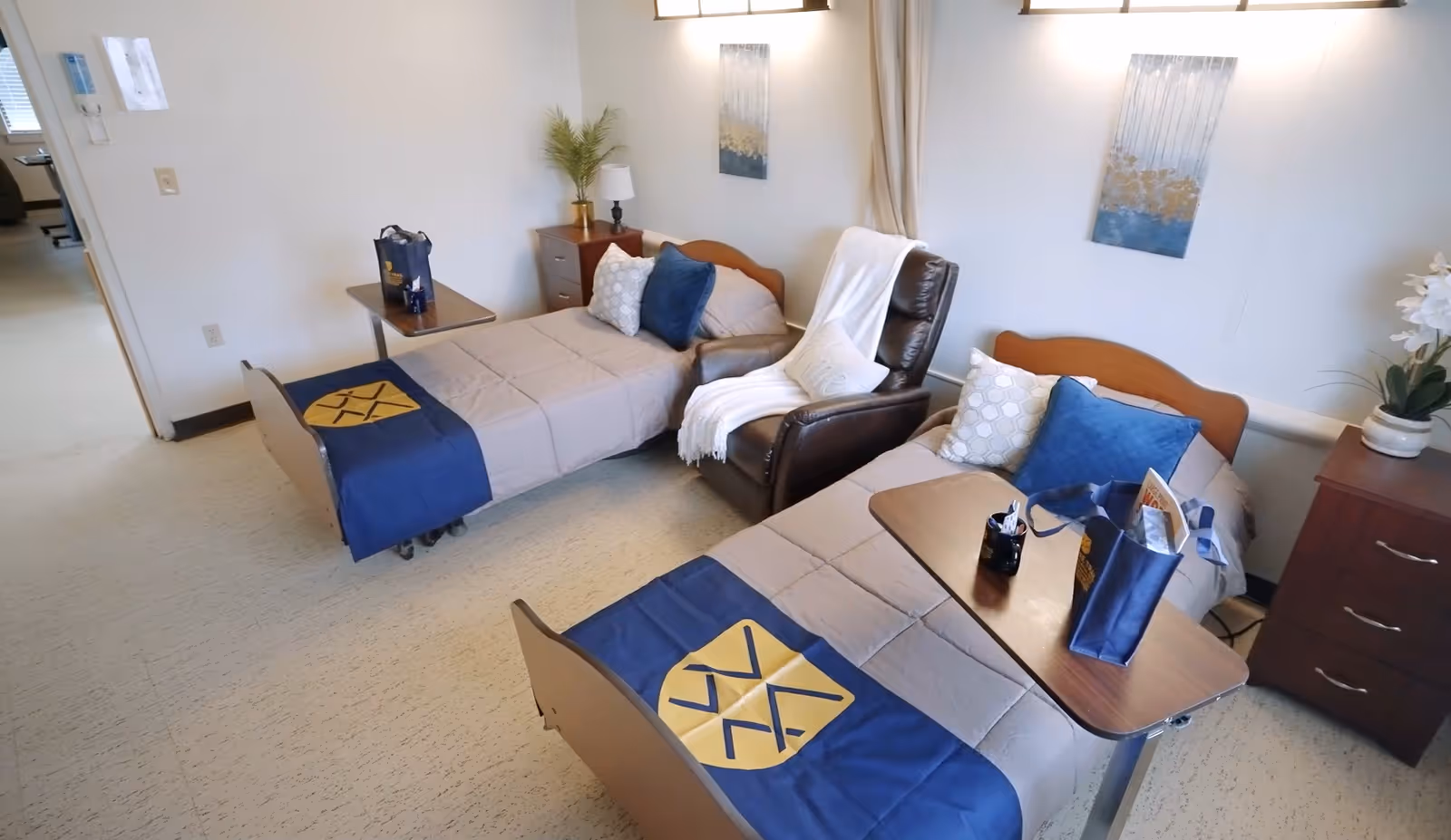 Shared senior care bedroom with two twin beds, a recliner between them, bedside tables and decorative accents.