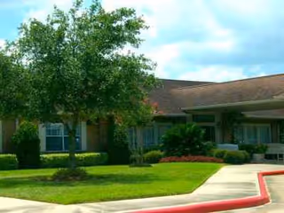 Exterior view of The Reserve at Pasadena, with trees, shrubs, and a red curb.