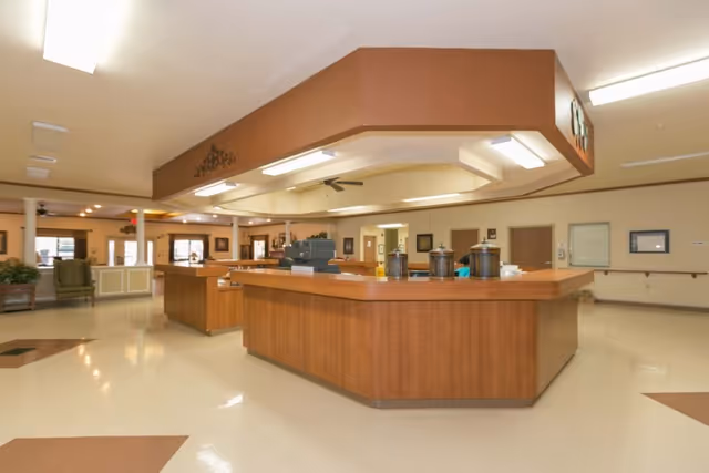 Interior view of the lobby at Misty Willow Healthcare & Rehabilitation Center, featuring a wooden reception desk and seating area with artwork on the walls.