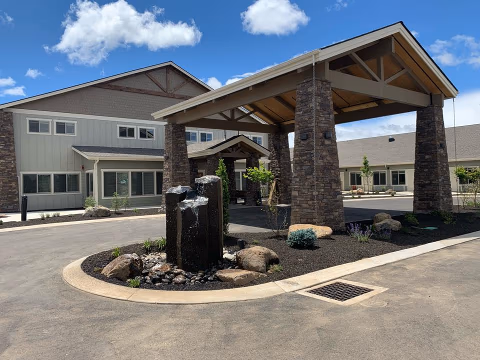 Entrance of The Lodge Retirement Community featuring a stone structure and landscaped area.