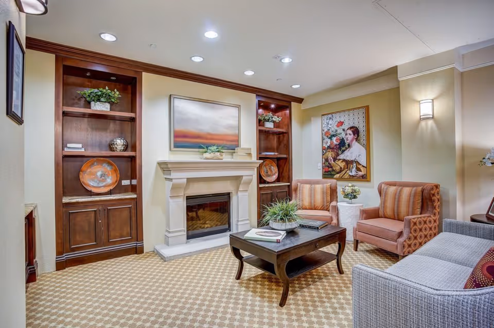 Cozy lounge with a fireplace, built-in wooden shelving, a coffee table and upholstered chairs.