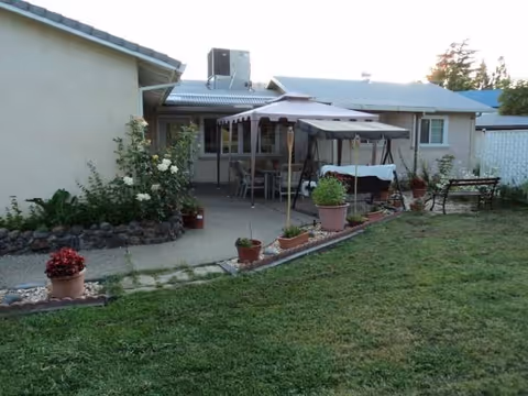 Exterior view of The Heights Care Home with patio, umbrellas, and potted plants.