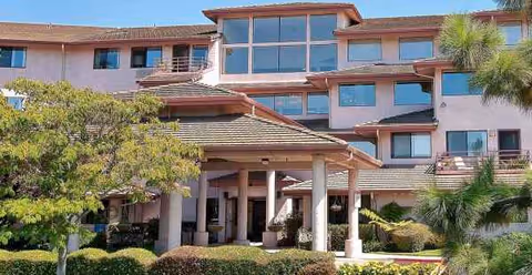 Front exterior view of Las Brisas Retirement Community with a covered entrance and landscaping