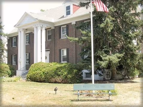 Front of Hazel L. Carpenter Adult Home, brick building with white columns and an American flag.