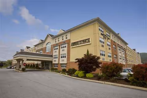 Large multi-story Ashbridge Manor senior living building with entrance canopy and landscaped front.