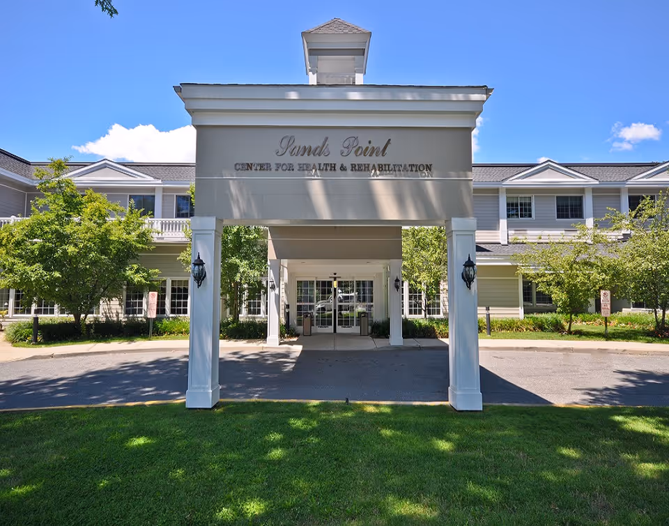 Exterior view of Sands Point Center entrance with a covered porte-cochère and green landscaping.