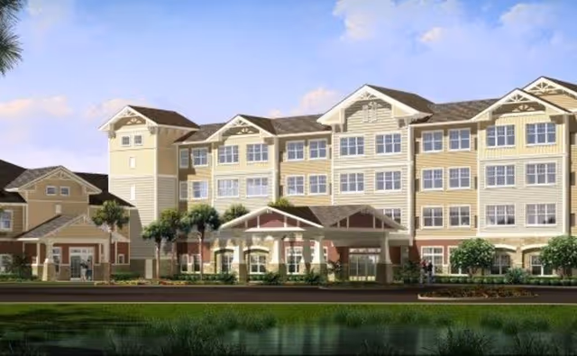 Front exterior of a multi-story senior living building with a covered entrance, palm trees, and a reflecting pond in front.