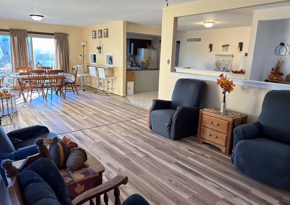 Spacious communal living area with blue chairs, a coffee table, and a dining nook.