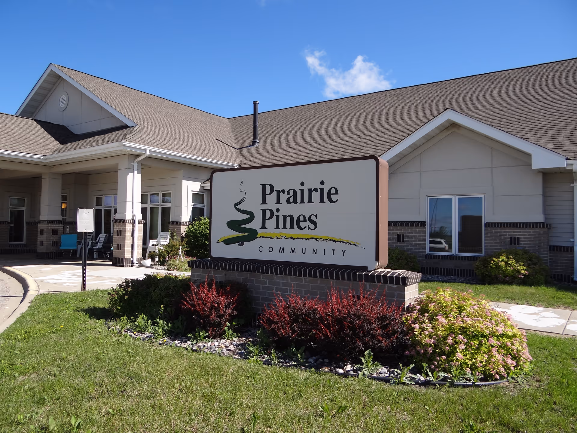 Exterior front entrance of the Prairie Pines Community building with a large sign and landscaped lawn.