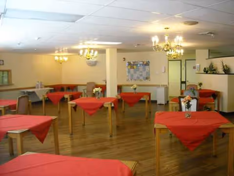 Palms nursing home dining room with red tablecloths and chandeliers.