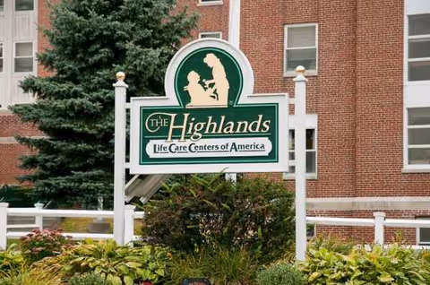 Front view of The Highlands sign with brick building and landscaping.