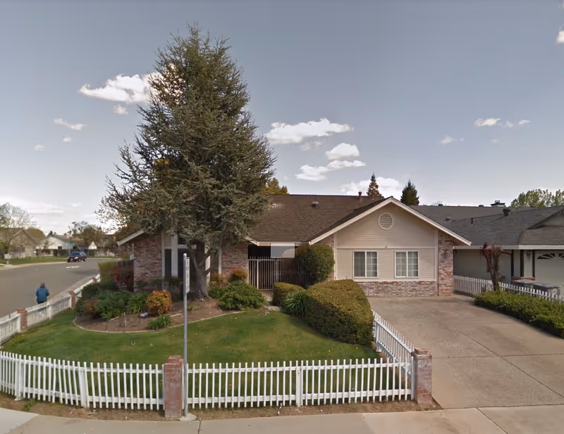 Laguna Park exterior: a single-story building with brick siding and a white picket fence.