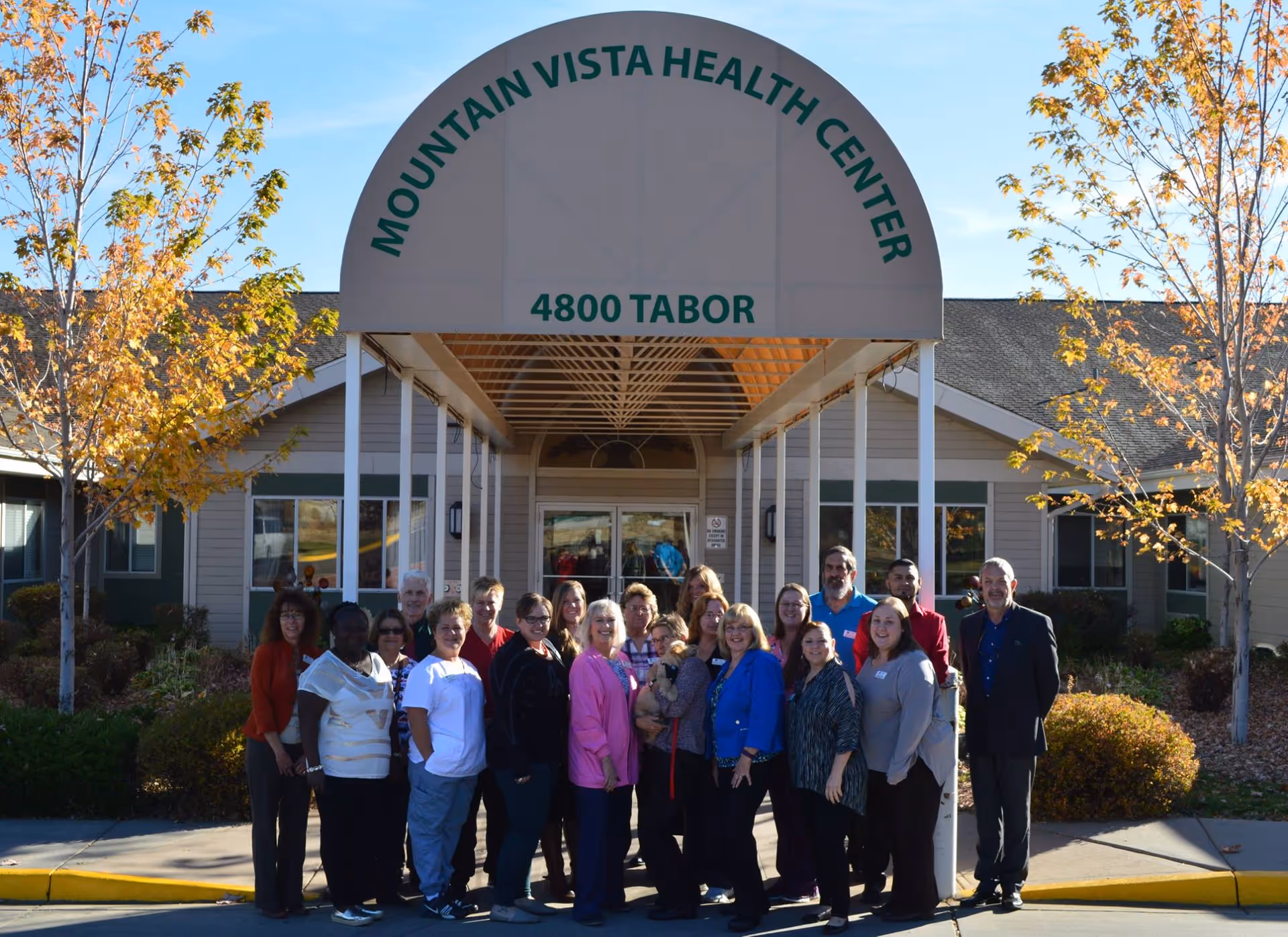 A group of people standing in front of the Mountain Vista Health Center entrance under an awning that reads "4800 Tabor".