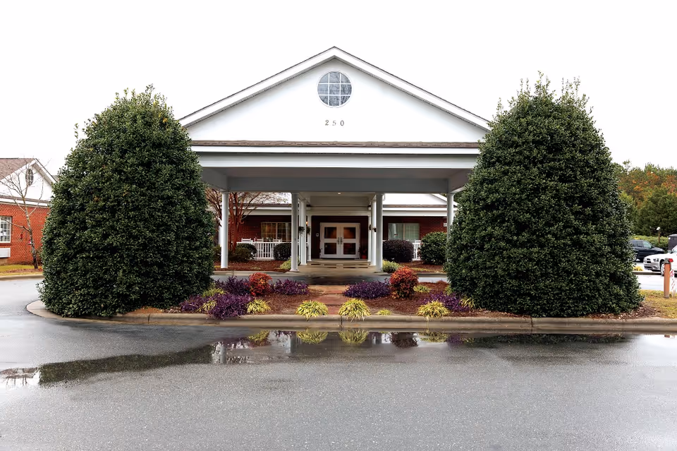 Meadowview senior living entrance with a covered porte-cochere and manicured shrubs.