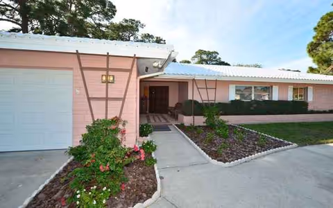Exterior view of Sea View Inn at Forest Lakes with pink walls and walkway.