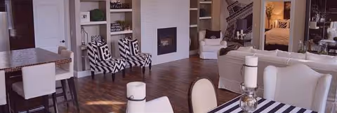 Open-concept living area in Mercy Family Home with striped chairs, white furniture, and a fireplace.
