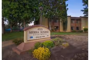 Exterior view of Sierra Sunrise Apartments front sign with greenery