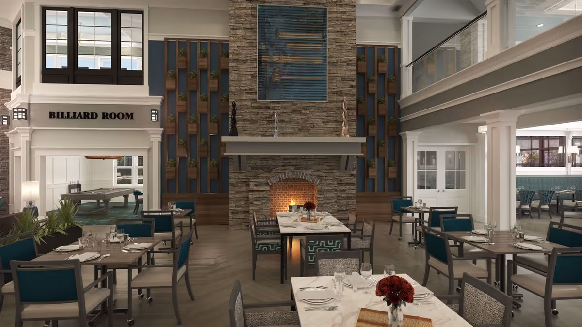 A spacious dining area with multiple tables set with plates, glasses, and silverware. The room features a large stone fireplace with a fire burning, flanked by decorative wooden panels with small plants. To the left, there is an entrance labeled 'Billiard Room' with a pool table visible inside. The dining area has teal and gray chairs and a high ceiling with a second-floor balcony overlooking the space.