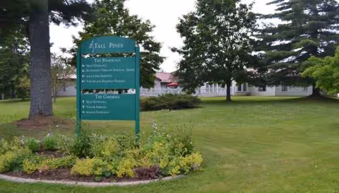 Tall Pines sign on a manicured lawn with a building in the background.