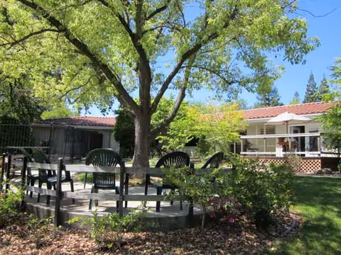 Outdoor seating area with trees and a single-story building at Olive Glen Main House.